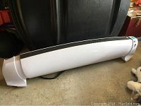 Full length view of white Enviro heater placed on floor showing curved shape and feet supports.