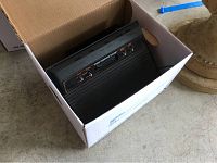 Atari 2600 console packed inside a cardboard box resting on a concrete floor.
