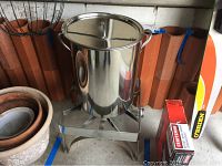 Full view of the deep fryer on stand with pot and lid, and a boxed Craftsman item in background