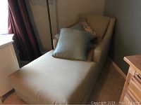 Sage green chaise with seat, backrest, arms, and three pillows placed on top.