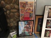 Two tall Buffalo Ranch western posters framed and leaning against a stone wall with a smaller framed print in front.