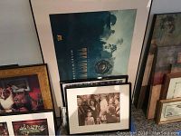 Framed nostalgic and artistic wall decor arranged leaning on a wall including movie posters and photography