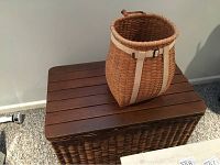 Wicker trunk with wooden top and backpack basket placed on top, showing texture and condition of wicker and wood.
