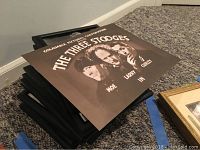 Small print of The Three Stooges leaning on black-framed art prints pile