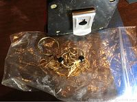 Two single hoop earrings, a pair of double hoop earrings with onyx beads, and gold fish-link bracelet in plastic bag