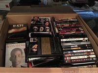 Large cardboard box filled with a diverse collection of DVDs visible from above.