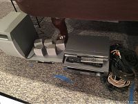 Overall view of the speaker system components including subwoofer, satellite speakers, DVD player, receiver, and cables on carpeted floor