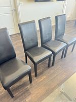 Four black high-back dining chairs lined up