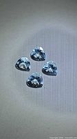 Four light blue pear-cut gemstones on neutral background