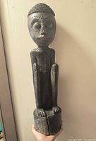 Full frontal view of carved wooden figure showing height, posture and bead accents
