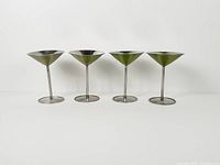 Four martini glasses side by side showing green enamel outside and stainless stems