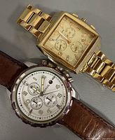 Fossil and Michael Kors watches side by side showing faces and bracelets