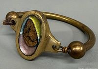 Full view of bronze bangle showing oval enamel plaque and round screw-end bead