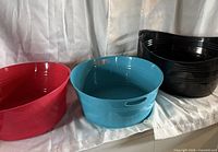 Red, teal and black plastic oval bins side by side on fabric backdrop