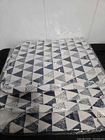 Three folded hampers, two geometric patterns stacked, wrapped in plastic.
