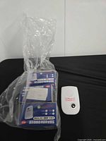 Loose white ultrasonic pest repeller beside three boxed units in plastic bag