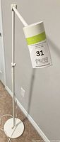 Full view of white floor lamp front angle showing base, pole, adjustable arm and head