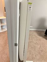 Mattress and part of white metal bed rail upright against wall