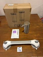 All lot items on table: boxed toilet paper holders, soap dispenser, soap refill pouch, suction grab bar