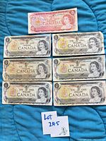 All seven banknotes laid out: one $2 on top, six $1 below