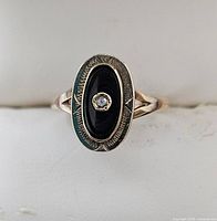Top view of oval black onyx ring with central diamond