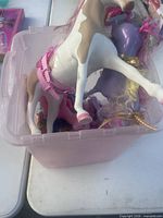 Pink storage bin containing assorted My Little Pony figures, visible large pony on top