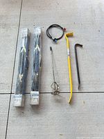 All six items laid out: two boxed sawhorse frames, mixing paddle, 36" yellow wrecking bar, smaller crowbar, hose with fittings
