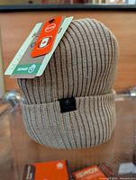 Full view of beanie showing color, ribbing, cuff, and tags attached