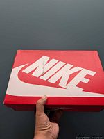 Red Nike shoe box top showing large Nike logo and visible tear