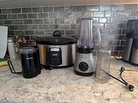 Slow cooker, blender with cup attached, second cup, Cuisinart grinder on countertop