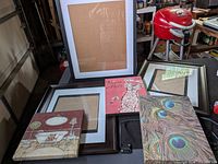 Group of four frames and three art prints displayed on table