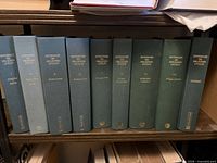 Nine cloth-bound volumes on shelf, spines visible