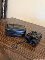 Binoculars beside carrying case on table showing overall appearance