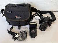 Full lot overview showing camera with lens, flash, webcam, cables, and bag