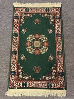 Full view of green Persian style rug with fringe