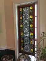 Full view of stained glass panel hanging in a doorway showing the entire wood frame and stained glass design.
