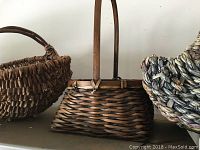 Close view of rectangular woven basket with handle and natural fiber weave alongside other baskets