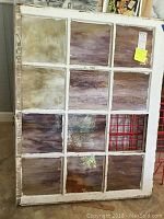 Wooden window sash with stained glass panes, one pane missing.