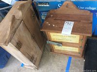 Photo showing wooden cabinet with two drawers and carved handle next to wooden suggestion box.