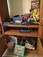 Wood cabinet shelves with toys, games, calculator, iPod and sunglasses