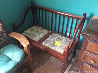 Front and side angle of the vintage wooden bench showing floral seat cushions and spindle backrest.