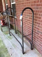 Full view of the steel tubular log holder showing its height and basic frame design against a brick wall.