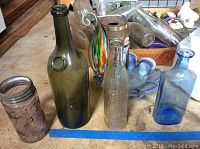Multiple glass bottles including green, lavender, clear, and blue seen on floor.