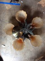 Top view of vintage pendant light showing six glass floral shades and central metal mounting plate.