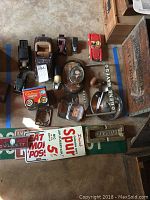 Top view of seven model cars, vintage signs, framed photos, ashtray, tobacco pipe, and other small items arranged on floor.
