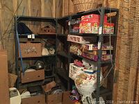 Wide view of three metal shelving units in basement with various stored household items.