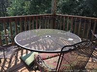 Complete set on deck showing round wrought iron table and four matching chairs with cushions.