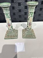 Front view of the pair of matching green porcelain candlesticks with floral panels