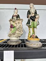 Both porcelain figurines side by side on shelf