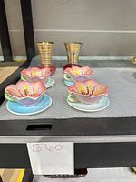 Group shot of four porcelain flower bowls on saucers with two cranberry glass bud vases